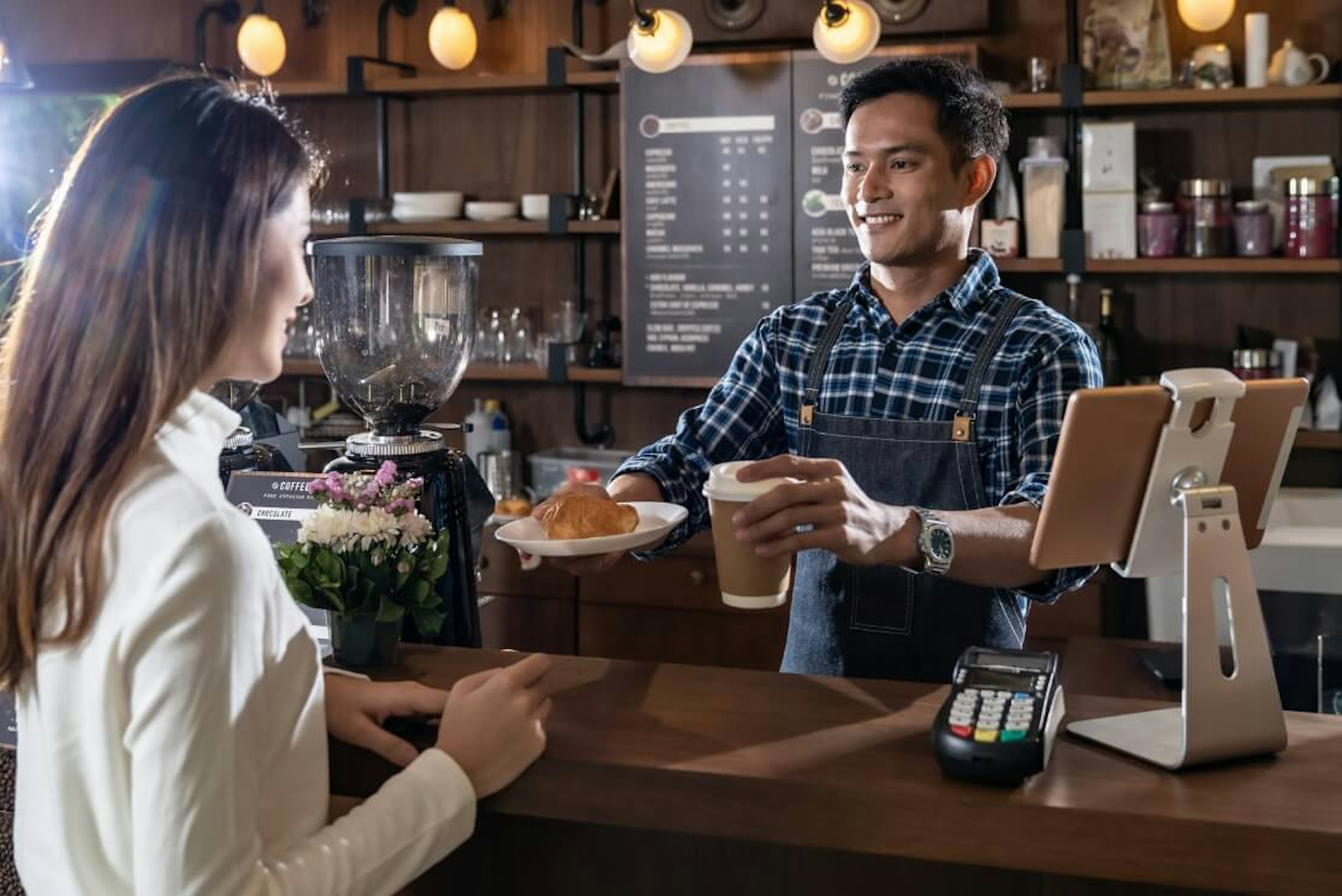 Un barista entrega un pan con café como parte del servicio y operación de una cafetería, que se obtiene al tomar un taller para abrir una cafetería como el nuestro.